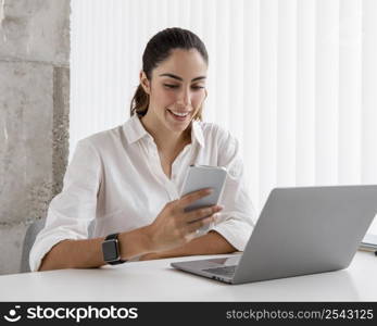 smiley businesswoman with smartphone laptop