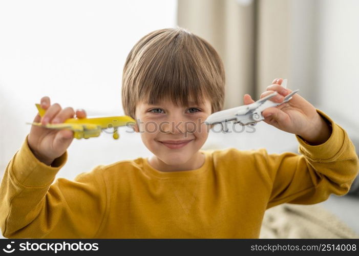 smiley child playing with airplane figurines home