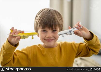 smiley child playing with airplane figurines home