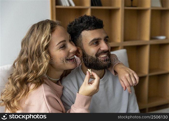 smiley couple eating popcorn watching movie home
