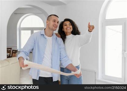 smiley couple holding house plans