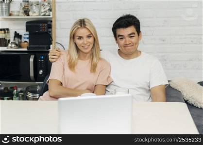 smiley couple home during pandemic looking laptop