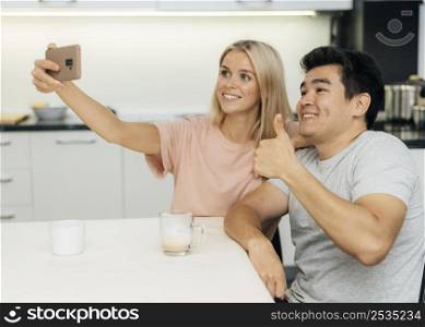 smiley couple home during pandemic taking selfie with smartphone