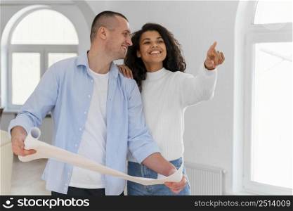 smiley couple inside their new home holding house plans
