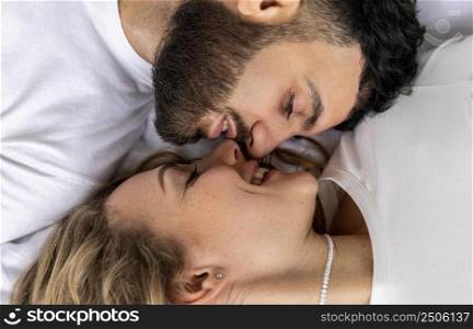 smiley couple kissing bed home