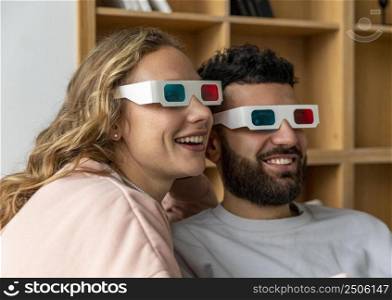 smiley couple watching movie home with three dimensional glasses