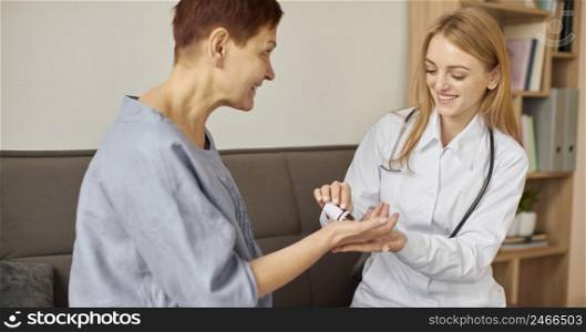 smiley covid recovery center female doctor giving elder patient pills