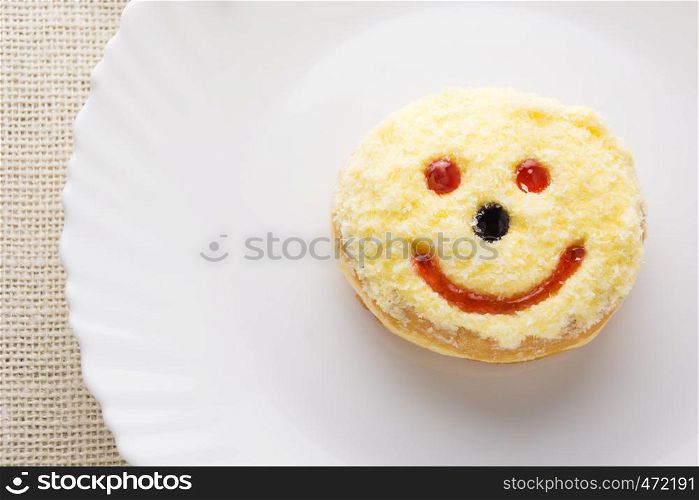 Smiley donut on a white plate, donut with white background