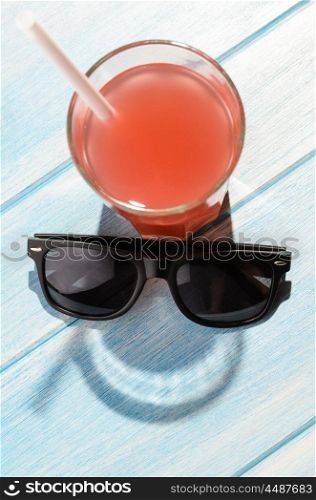 smiley drink on beach table. creative summer smile. red drink in glass on blue summer table