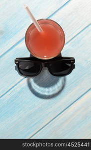 smiley drink on beach table. creative summer smile. red drink in glass on blue summer table