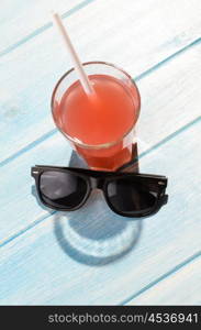 smiley drink on beach table. creative summer smile. red drink in glass on blue summer table