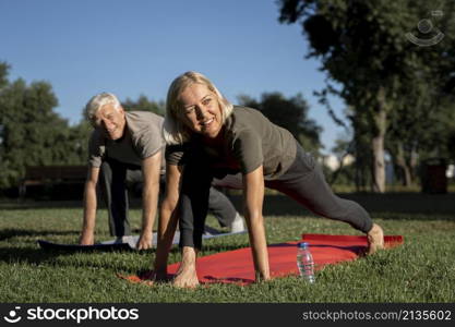 smiley elder couple practicing yoga outdoors