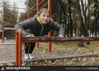 smiley elder woman doing push ups outdoors