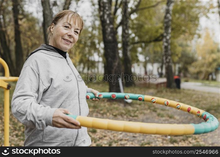 smiley elder woman outdoors working out with equipment