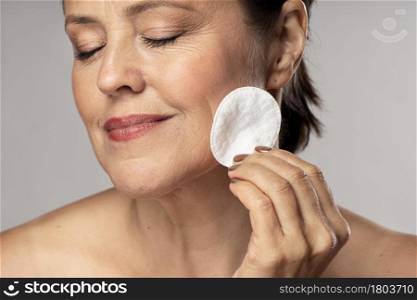 smiley elder woman using cotton pad make up removal