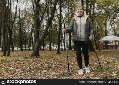 smiley elder woman with trekking sticks copy space