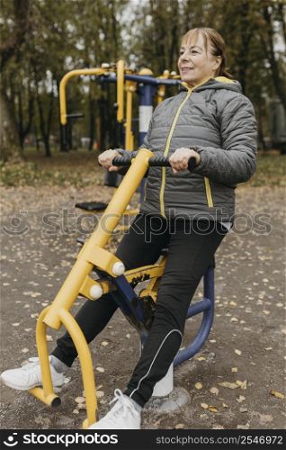 smiley elder woman working out with equipment outdoors