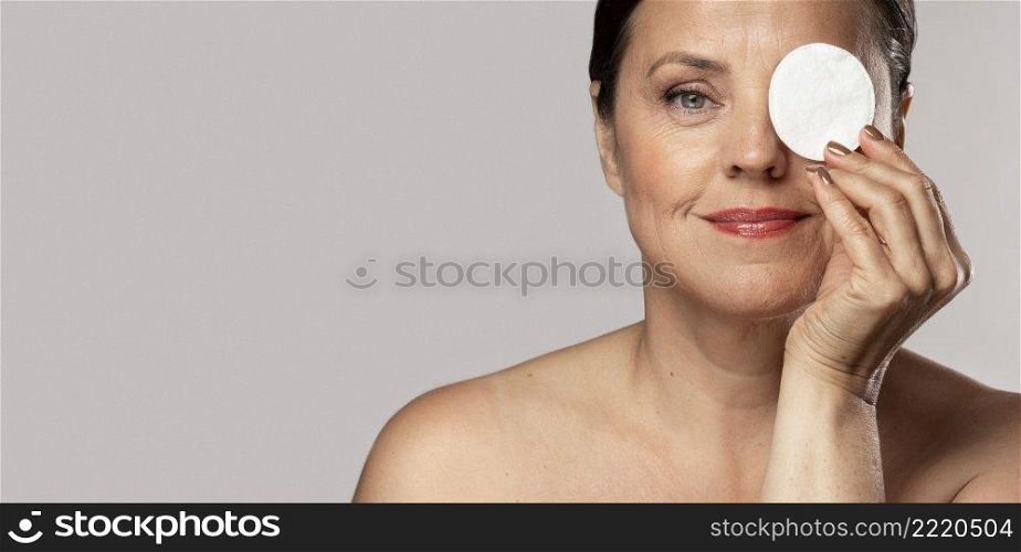 smiley elderly woman posing with cotton pad make up removal copy space