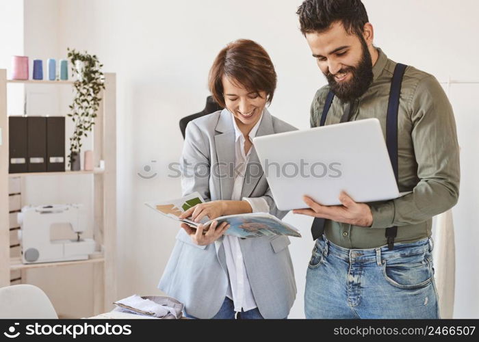 smiley fashion designers working atelier with laptop