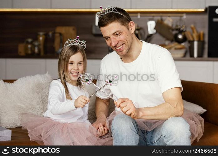 smiley father daughter playing with tiara wand