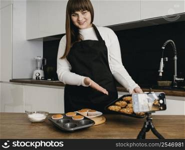 smiley female blogger recording herself while preparing muffins
