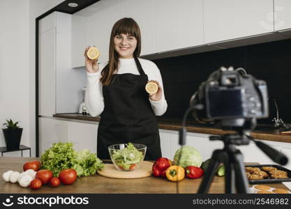 smiley female blogger recording herself while preparing salad