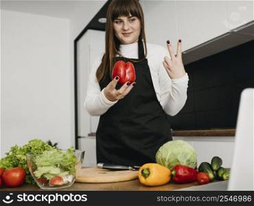 smiley female blogger streaming cooking with laptop