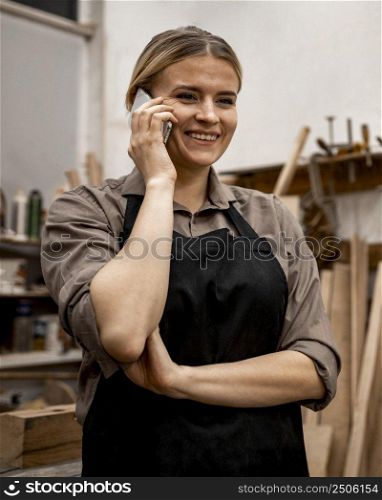 smiley female carpenter using smartphone work