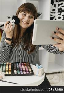 smiley female make up blogger with streaming with tablet home