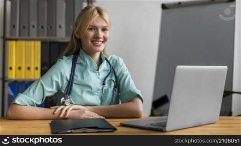 smiley female nurse office with stethoscope laptop