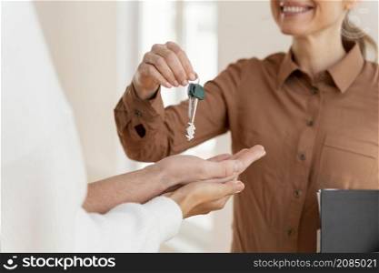 smiley female realtor handing couple keys their new home