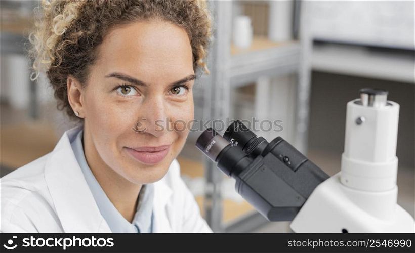 smiley female researcher laboratory using microscope
