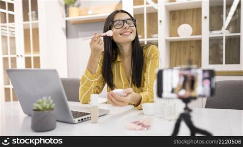 smiley female vlogger home with smartphone brush