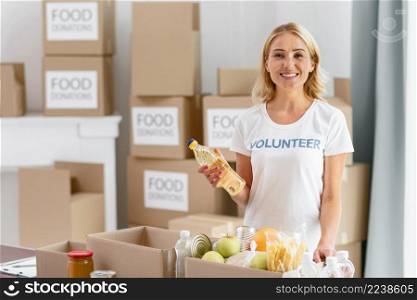 smiley female volunteer preparing box with food donation