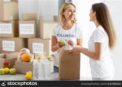 smiley female volunteers putting food bags preparing them donation