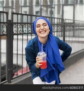 smiley girl wearing hijab holding smoothie