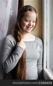 smiley girl with down syndrome posing by window