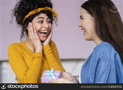 smiley happy women giving each other gifts