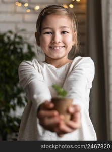 smiley little girl holding plant pot home
