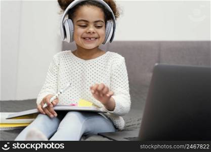 smiley little girl using laptop online school
