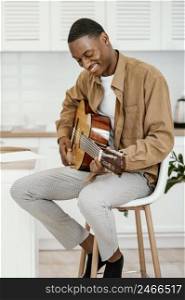 smiley male musician home chair playing guitar
