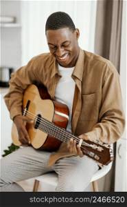 smiley male musician home playing guitar