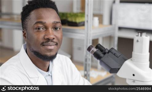 smiley male researcher laboratory using microscope