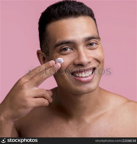 smiley man applying cream his face
