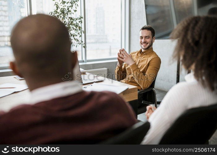 smiley man talking his colleagues during meeting