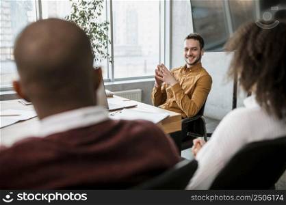 smiley man talking his colleagues during meeting
