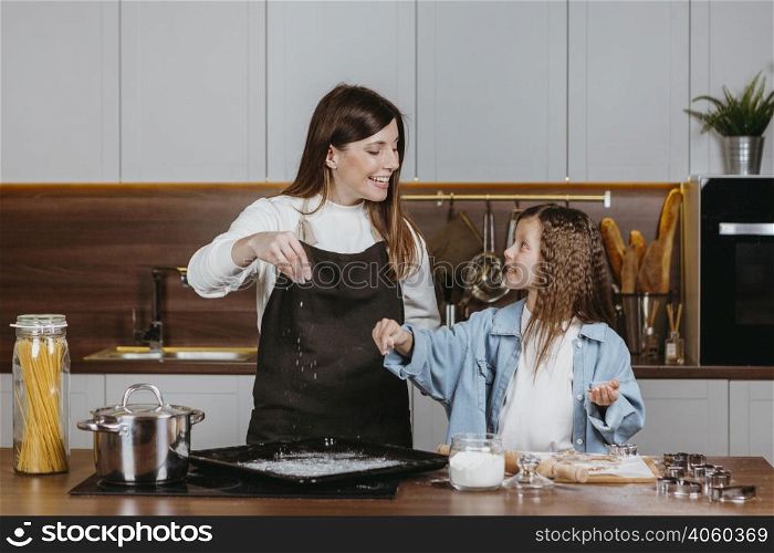 smiley mother daughter cooking together kitchen home