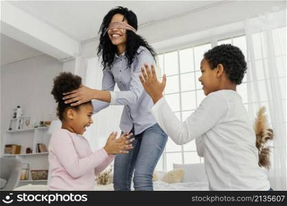 smiley mother playing with her children home while blindfolded