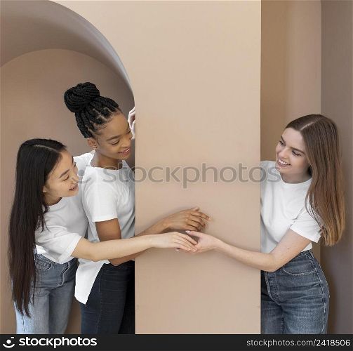 smiley multicultural women near wall