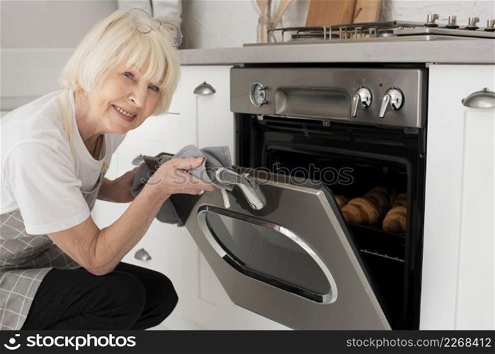 smiley old woman opening door oven